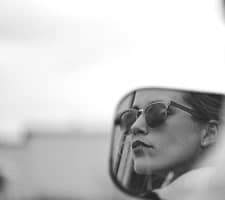 Teenager wearing sunglassess looking in the distance from the driver-side window