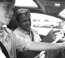 Driver instructor in the front seat of the car talking to a student driver in the passenger seat
