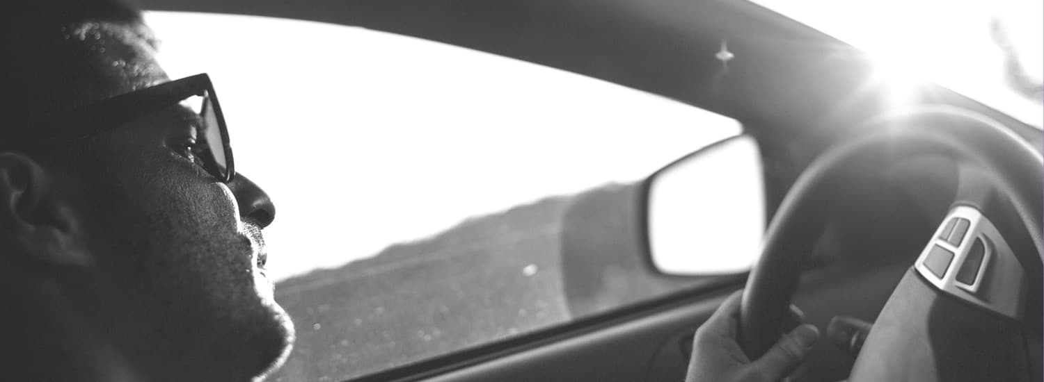 Close up on man with glasses clutching the steering wheel